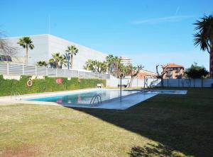 a swimming pool in a park with palm trees and a building at Rey apartment in Vilassar de Mar