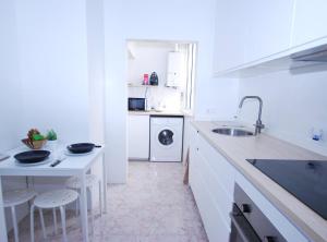 a white kitchen with a sink and a washing machine at Can Josep in Vilassar de Mar