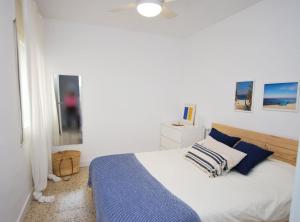 a white bedroom with a bed and a ceiling fan at Can Josep in Vilassar de Mar