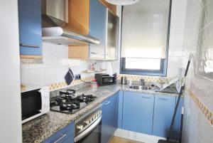 una piccola cucina con armadi blu e lavandino di Waves and sky a Montgat Altre 14 foto