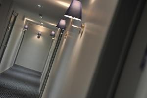 a hallway with two lights on the wall and a mirror at Mercure Paris Saint Cloud Hippodrome in Saint-Cloud
