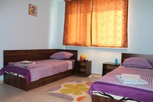 SilistraにあるHostel Victoriaの紫とオレンジのシーツが備わる客室のベッド2台