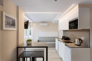 a kitchen with white cabinets and a table in it at Aparthotel Vilassar in Vilassar de Mar