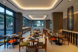 SimparにあるHotel Neo Kota Baru Parahyanganのテーブルと椅子と窓のあるレストラン