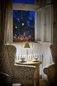 Una mesa en una ventana con dos tazas y una lámpara. en Hotel At the Golden Scissors, en Praga