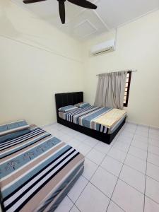 two beds in a room with a ceiling fan at Pangkor Homestay in Pangkor