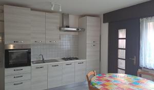 eine Küche mit weißen Schränken und einem Waschbecken und einem Tisch in der Unterkunft casa palma in Levico Terme