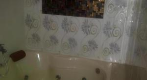 y baño con bañera blanca y cortina de ducha. en Permata Hotel, en Gurungsang