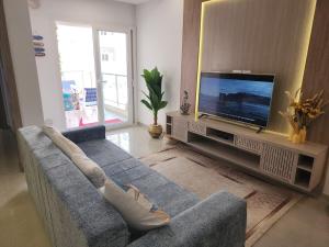 a living room with a blue couch and a flat screen tv at Fantastic Appartment SeaView Sousse in Akouda
