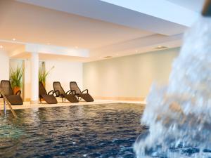 ティメンドルファー・シュトラントにあるSeeHuus Lifestyle Hotelの椅子と噴水のあるプール