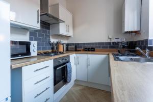 een keuken met witte kasten en een spoelbak bij Beaconsfield Stay Family & Work Friendly in Darlington