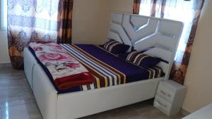 a bedroom with a white bed with a blue blanket at 2-bedroom equipped apartment in Bakote