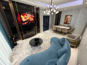 een woonkamer met een blauwe bank en een tv bij Tashkent City Apartments 1A in Tasjkent