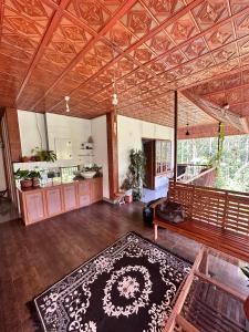 a large living room with a wooden ceiling and a rug at Avocado Orchards - Home Stay in Kenichira