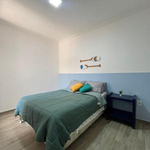 um quarto com uma cama com um cobertor verde em Studio no Centro com ESTACIONAMENTO GRÁTIS em Poços de Caldas
