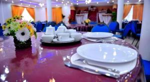 uma mesa com pratos brancos e guardanapos em Hotel Glee em Challi