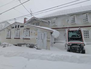 a truck parked in front of a house covered in snow at Hachiko Inn in Myoko