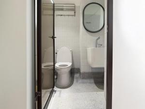 ein Badezimmer mit Toilette, Waschbecken und Spiegel in der Unterkunft Brown H in Pom Prap