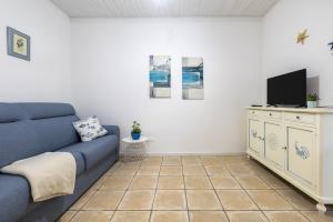 een woonkamer met een blauwe bank en een tv bij Su Marconi Home- Alghero in Alghero