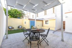 een patio met een tafel en stoelen onder een witte pergola bij Su Marconi Home- Alghero in Alghero