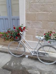 een witte fiets geparkeerd naast een gebouw met bloemen bij Casa Ninu' in Maruggio