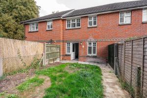 ein Backsteinhaus mit einem Zaun davor in der Unterkunft Modern Two Bedroom Home with Parking in Sherborne Saint John