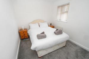 ein Schlafzimmer mit einem weißen Bett mit zwei Kissen darauf in der Unterkunft Modern Two Bedroom Home with Parking in Sherborne Saint John