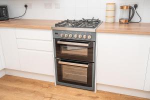 einen Edelstahlherd in einer Küche mit weißen Schränken in der Unterkunft Modern Two Bedroom Home with Parking in Sherborne Saint John