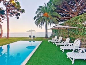 une piscine avec chaises et parasols au bord de l'océan dans l'établissement Premium Habitat Les Villes, à Arenys de Mar