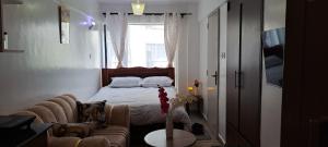 a bedroom with a bed and a couch and a window at The cozy nook - Thindigua in Kiambu