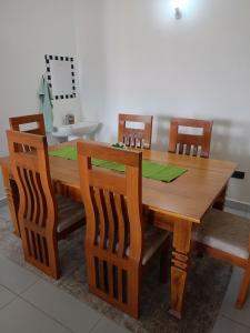 een houten eettafel met stoelen en een wastafel bij Tausi Home in Mombasa