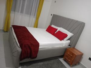 een bed met twee rode kussens op een kamer bij Tausi Home in Mombasa
