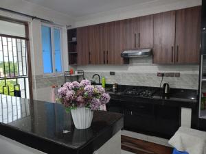 een keuken met een vaas met paarse bloemen op een aanrecht bij Tausi Home in Mombasa