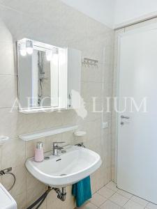 un bagno bianco con lavandino e specchio di Fortuna a Campese