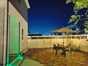 una mesa, sillas y una sombrilla en el patio en Ciao No,361 - Vacation STAY 61635v, en Tsukuba