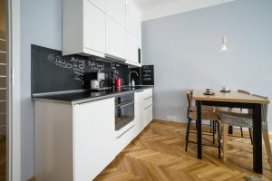 a kitchen with white cabinets and a small table at SmileApartment Partyzantów in Gdynia