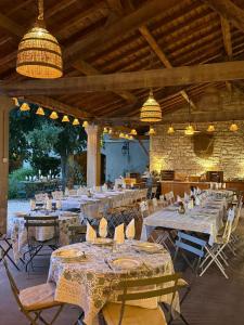 ein Restaurant mit langen Tischen, Stühlen und Lampen in der Unterkunft HOTEL et APPARTEMENTS DOMAINE DES CLOS - Teritoria in Beaucaire