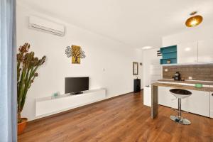a kitchen with white walls and a flat screen tv at Didi`s Stylish Studio - Seaview & Pool Backyard in Varna City