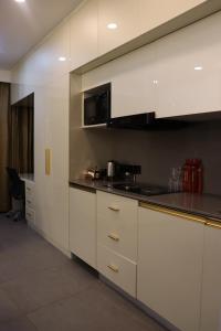 een keuken met witte kasten en zwarte aanrechtbladen bij High Sky inn in Noida +3 foto's