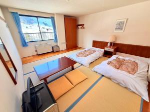 een kamer met 2 bedden, een bureau en een televisie bij Powder Base Naeba in Yuzawa +5 foto's