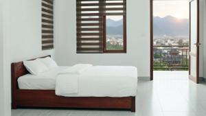 Un dormitorio blanco con una cama y un balcón. en Trang an Apartment, en Kon Rung (1)