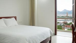Un dormitorio con una cama blanca y un balcón. en Trang an Apartment, en Kon Rung (1)