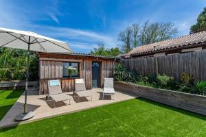 eine Terrasse mit Stühlen und einem Sonnenschirm im Hof in der Unterkunft Villa Rose des Sables, 100m de la Plage et Centre in Lège-Cap-Ferret