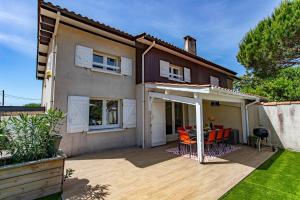 ein Haus mit einer Terrasse mit Stühlen und einem Tisch in der Unterkunft Villa Rose des Sables, 100m de la Plage et Centre in Lège-Cap-Ferret