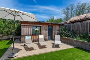 eine Terrasse mit 4 Stühlen und einem Sonnenschirm in der Unterkunft Villa Rose des Sables, 100m de la Plage et Centre in Lège-Cap-Ferret