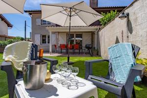 ein Tisch mit Weingläsern und einem Sonnenschirm in der Unterkunft Villa Rose des Sables, 100m de la Plage et Centre in Lège-Cap-Ferret + 21 Fotos