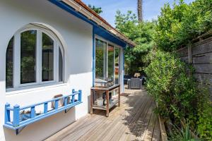 ein Haus mit einer Holzterrasse mit einem Fenster in der Unterkunft Villa 3 chambres dans le centre du Cap Ferret in Lège-Cap-Ferret