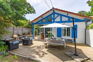 ein blau-weißes Haus mit einem Tisch und einem Sonnenschirm in der Unterkunft Villa 3 chambres dans le centre du Cap Ferret in Lège-Cap-Ferret