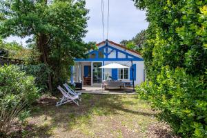 ein blau-weißes Haus mit einem Stuhl im Hof in der Unterkunft Villa 3 chambres dans le centre du Cap Ferret in Lège-Cap-Ferret