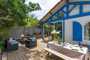 eine Terrasse mit einem Tisch und einem blauen Gebäude in der Unterkunft Villa 3 chambres dans le centre du Cap Ferret in Lège-Cap-Ferret + 60 Fotos